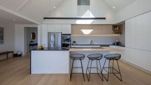 A modern kitchen with a central island, bar stools, and a skylight. - Miharo Wanaka Retreat | Spa, BBQ & Mountain Views (Wānaka)
