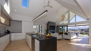 A spacious kitchen with a large island, modern appliances, and a view of the outdoors. - Miharo Wanaka Retreat | Spa, BBQ & Mountain Views (Wānaka)