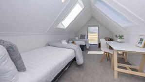 A modern, compact room with a sloped ceiling, a bed, a small desk, and a chair. - Miharo Wanaka Retreat | Spa, BBQ & Mountain Views (Wānaka)