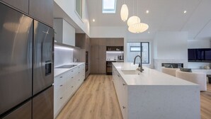 A modern kitchen with a large island, stainless steel appliances, and a skylight. - Marjon Peak Retreat | Spa, Pool & Mountain Views (Wānaka)