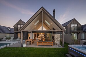 A modern house with a large patio, a hot tub, and a pool.
