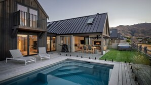 A modern house with a swimming pool, outdoor seating, and a fireplace. - Marjon Peak Retreat | Spa, Pool & Mountain Views (Wānaka)