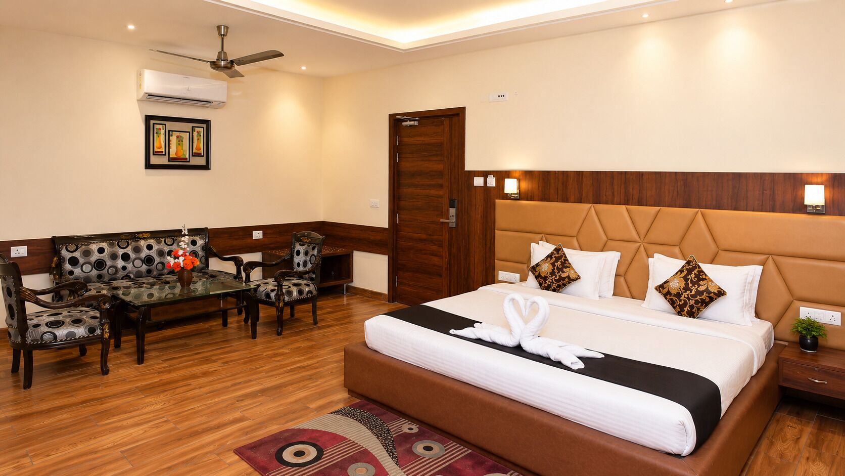 A hotel room with a bed, a sofa, a dining table, and chairs.