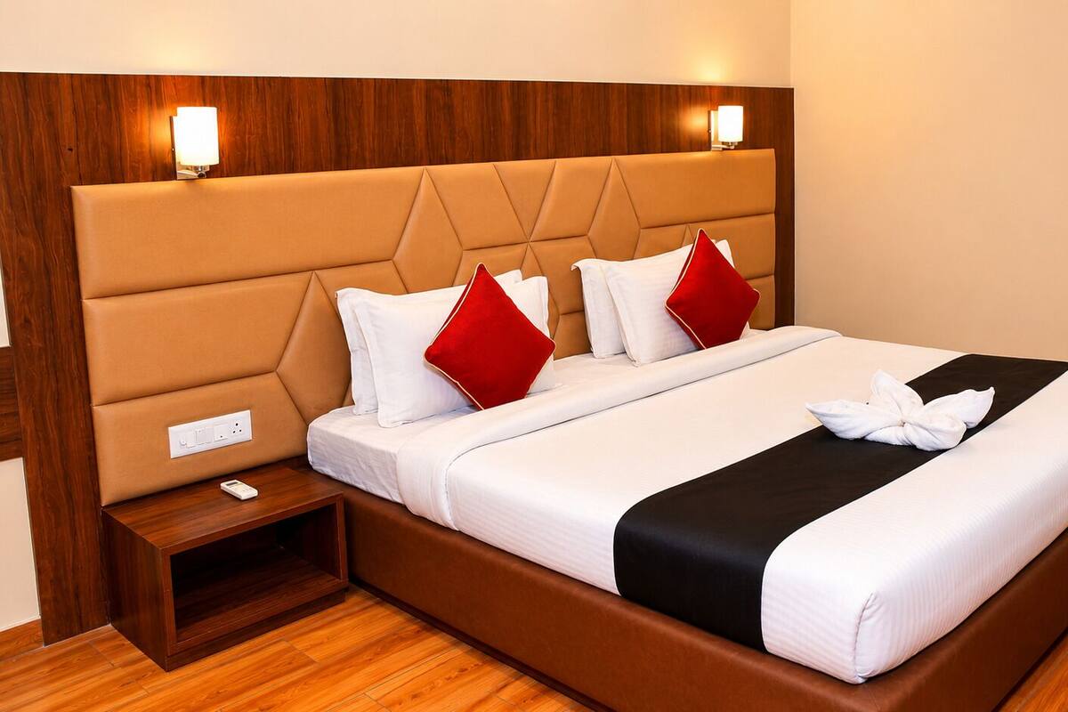 A hotel room with a large bed, a wooden headboard, bedside lamps, and a nightstand.