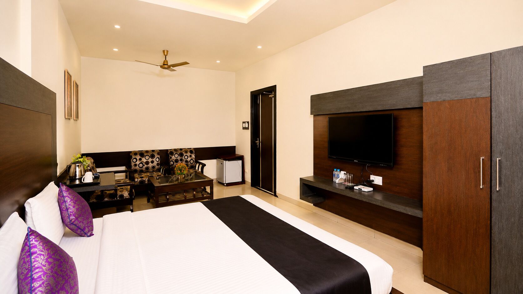 Une chambre d’hôtel moderne dotée d’un grand lit, d’une télévision à écran plat, d’un bureau avec une chaise et d’un ventilateur de plafond.