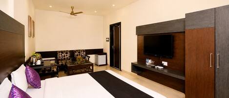 Une chambre d’hôtel moderne dotée d’un grand lit, d’une télévision à écran plat, d’un bureau avec une chaise et d’un ventilateur de plafond.