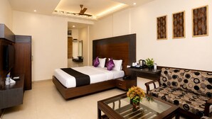 A hotel room with a bed, a sofa, a coffee table, a TV, and a desk. - Hotel Bhagyaraj Palace - Best Hotel In Kanpur (Kanpur)