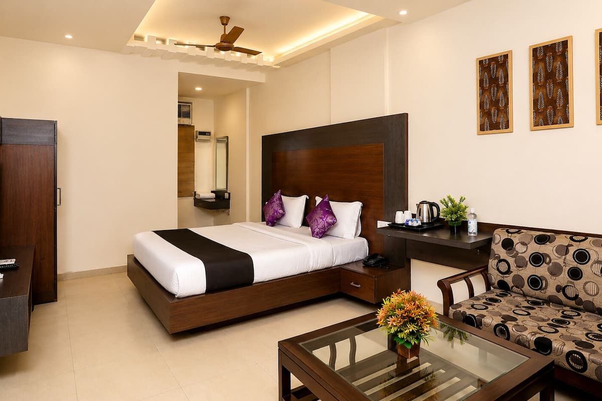 A hotel room with a bed, a sofa, a coffee table, a TV, and a desk.