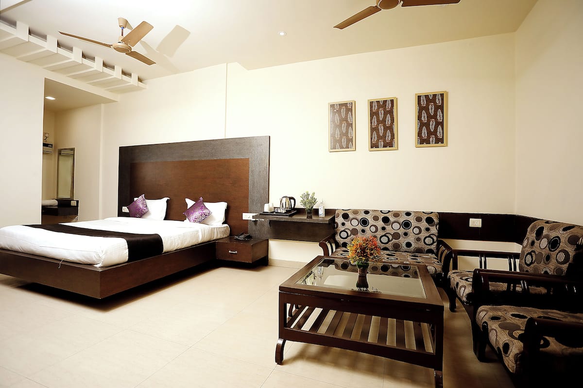 A modern bedroom with a bed, a sofa, a coffee table, and a ceiling fan.