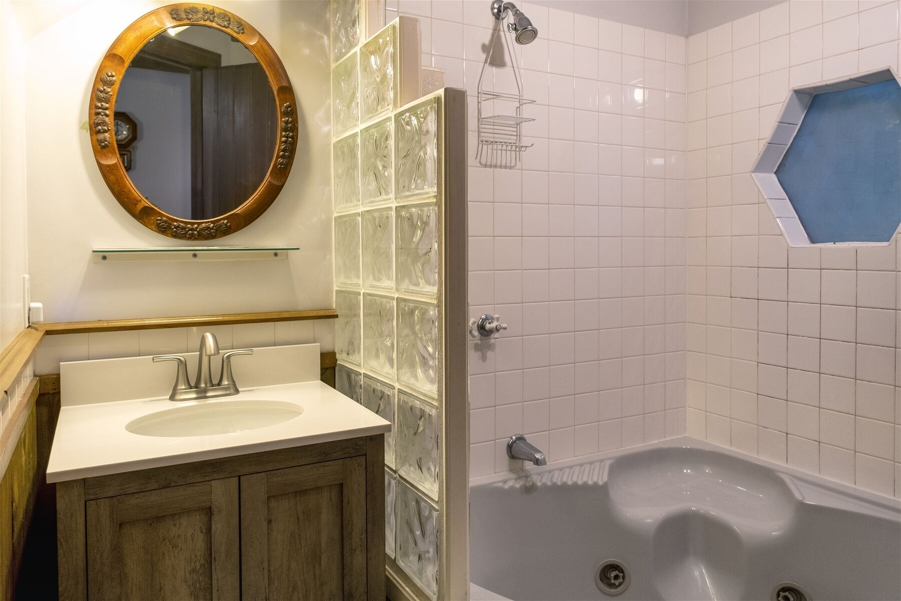 A bathroom with a wooden vanity, a glass shower enclosure, and a bathtub.