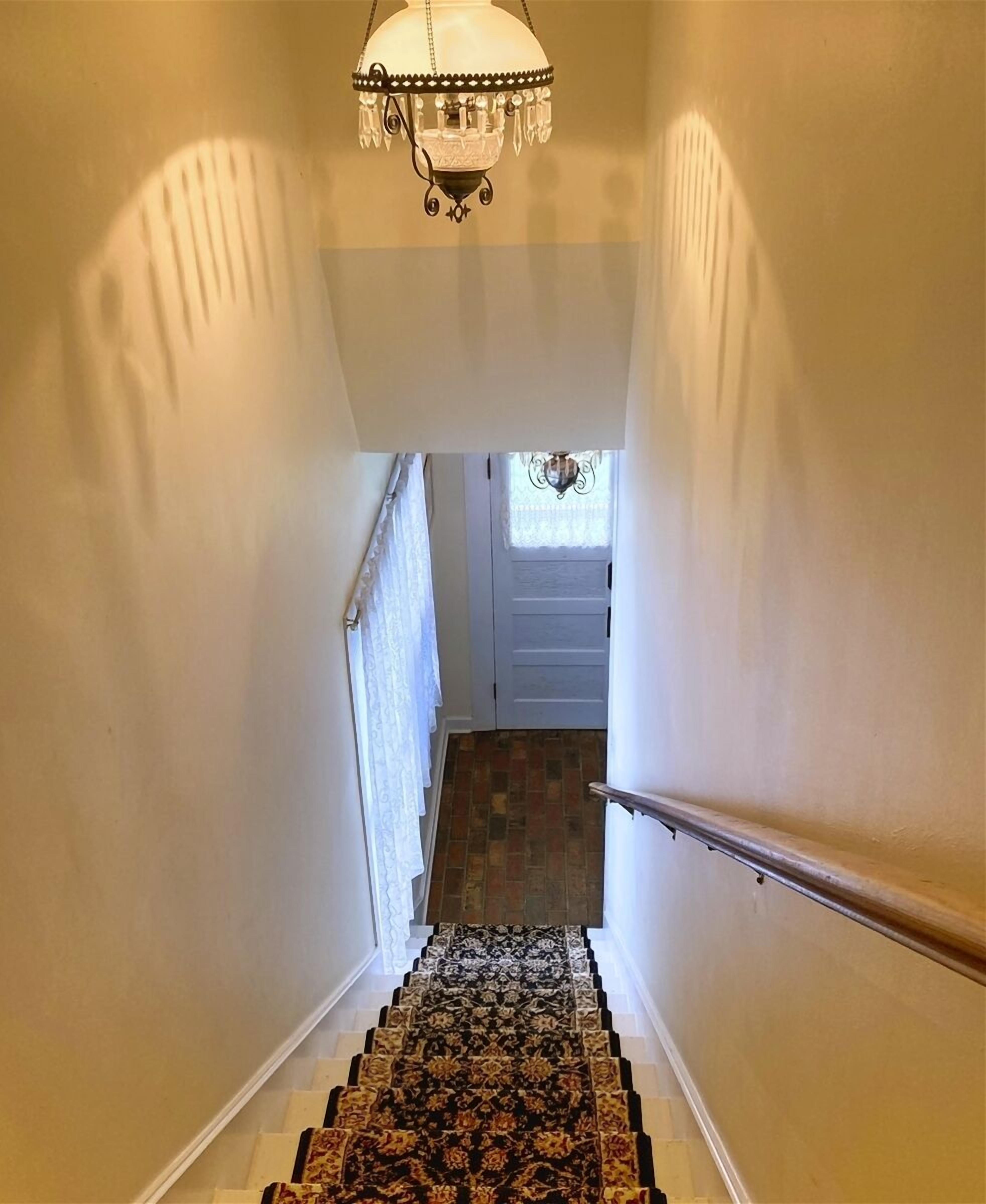 A staircase with patterned carpet leading to a door with a window.