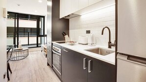 A modern kitchen with dark cabinets, a white countertop, and stainless steel appliances. - Full amenities 1-bedroom studio in CBD with pool (Auckland)
