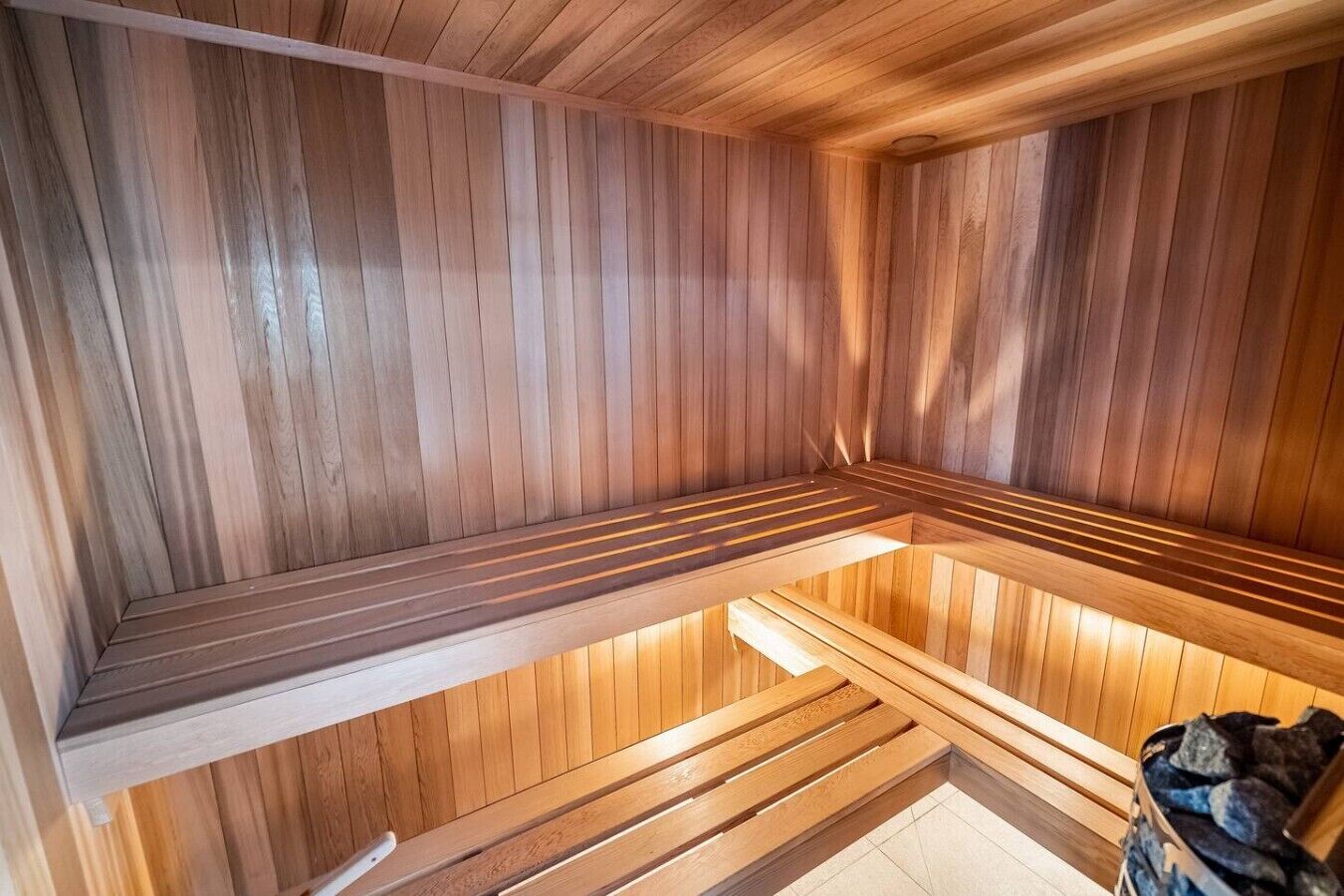 Un sauna avec des bancs en bois et un banc doté d’un dossier.