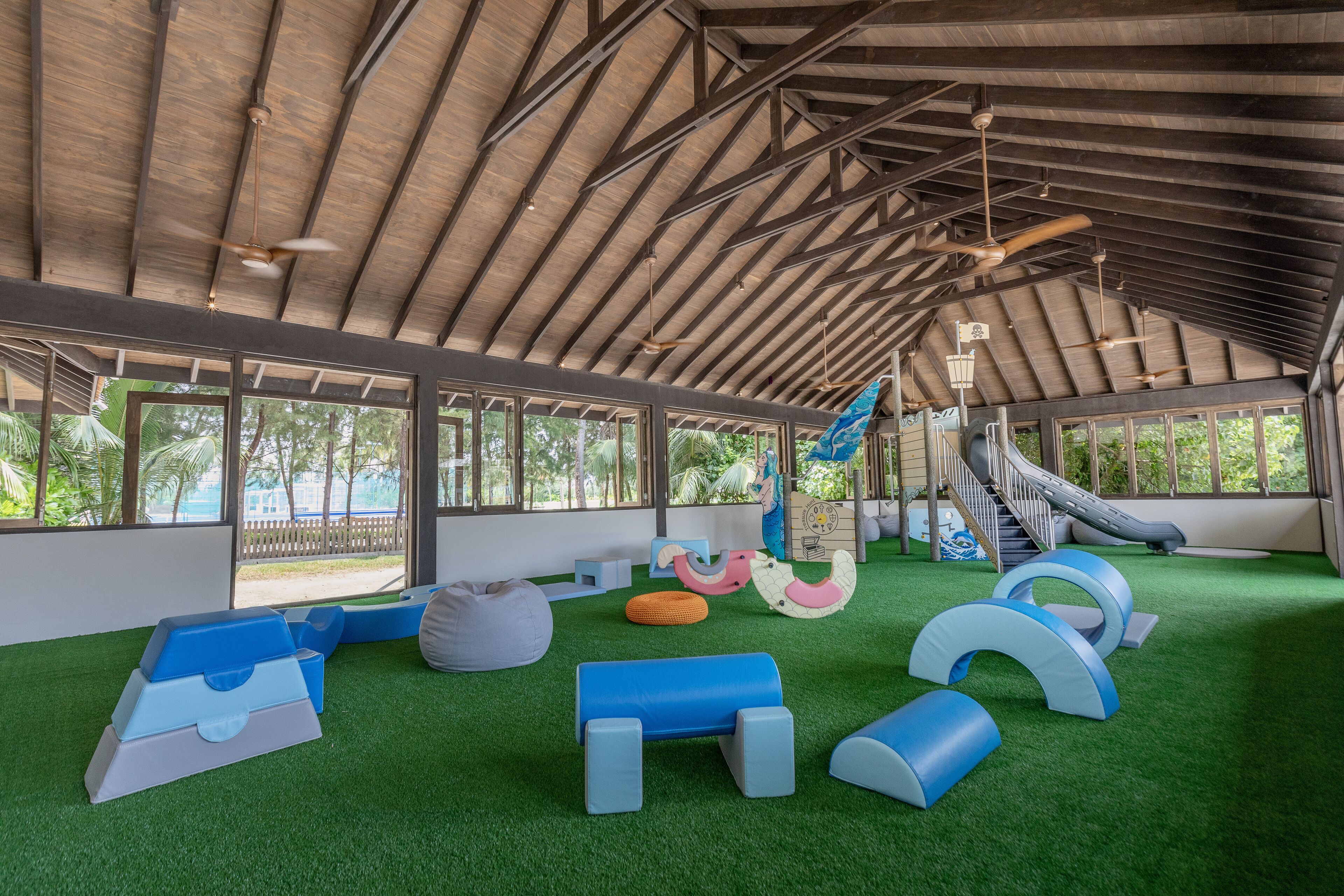 A covered play area with artificial turf, play structures, and a slide.