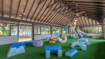 A covered play area with artificial turf, play structures, and a slide.