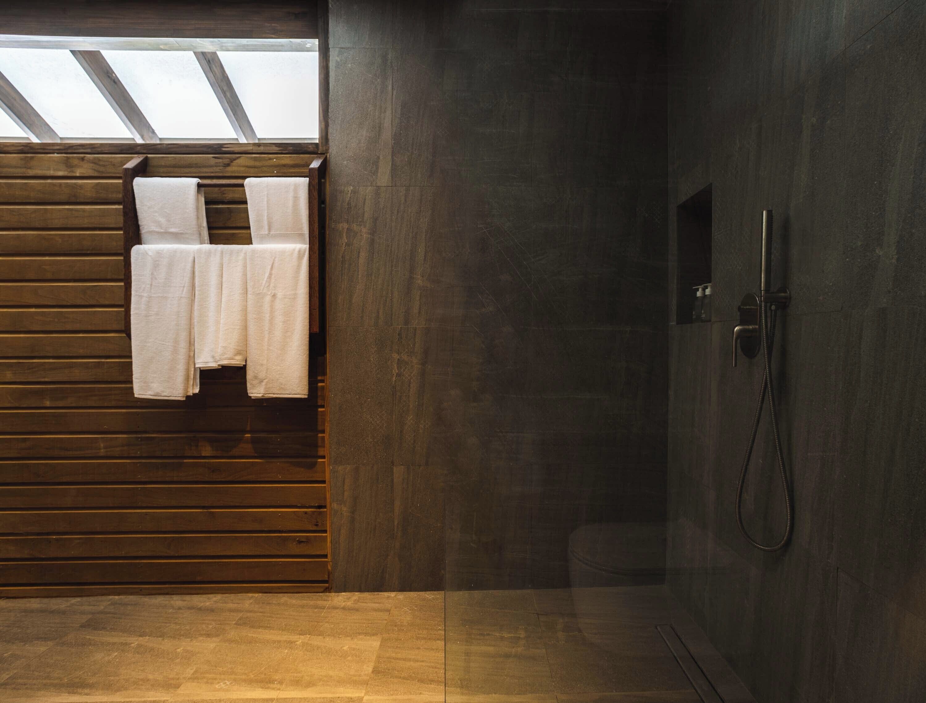 Ein modernes Badezimmer mit einer Wand aus Holzlatten, einem Glas-Skylight und einer Duschkabine.