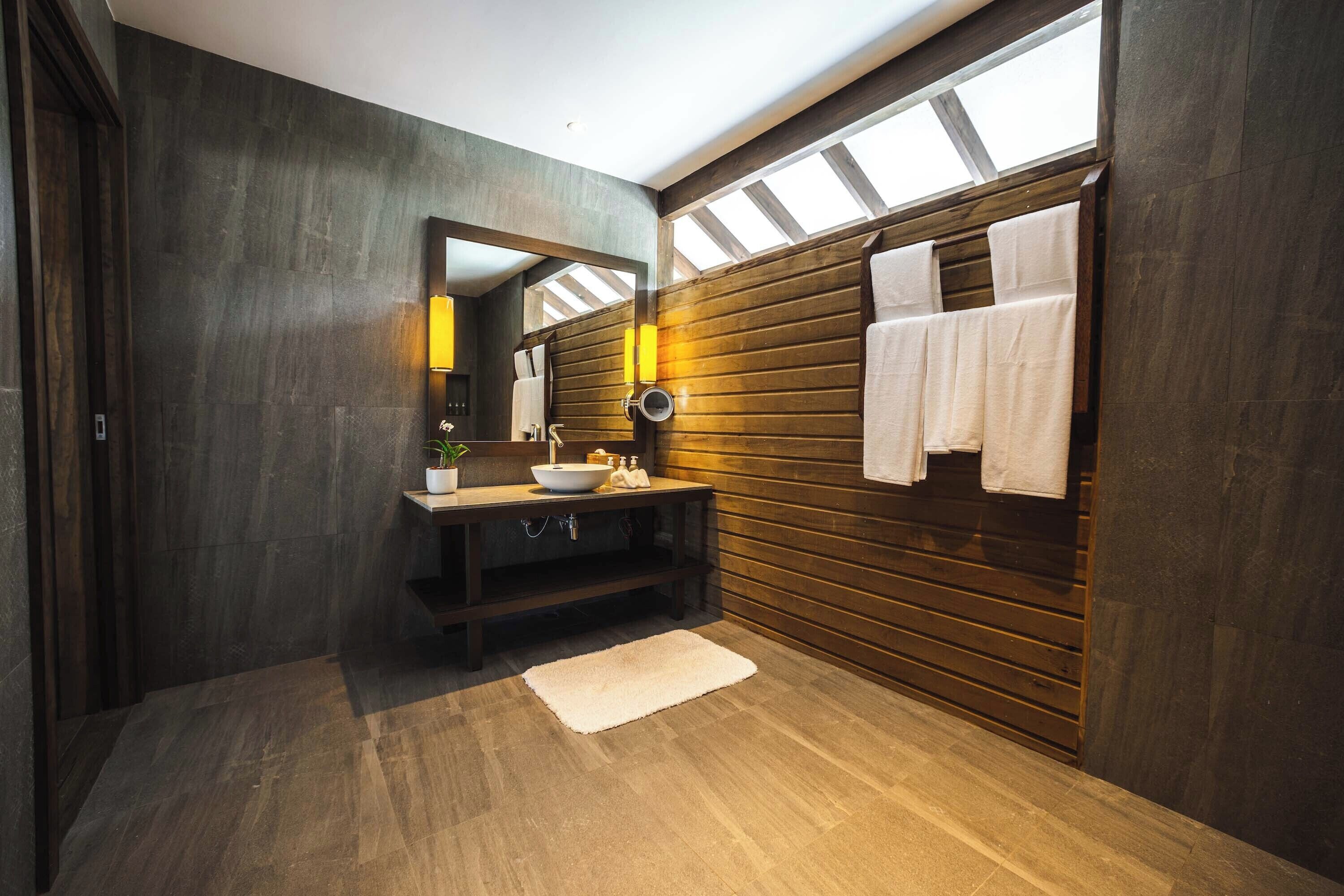 Un baño moderno con un tocador de madera, un espejo grande y un perchero para toallas.