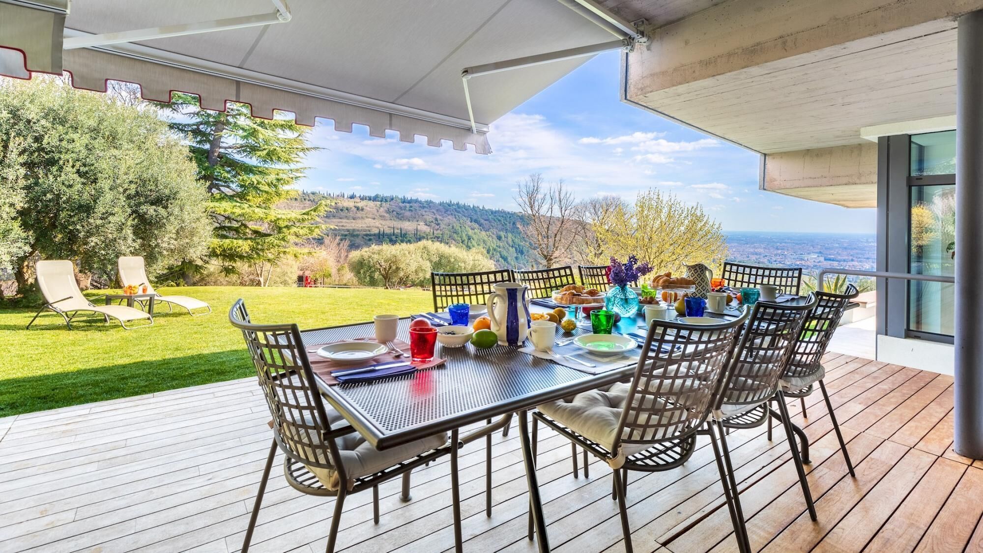 An outdoor dining area with a table set for four, surrounded by chairs, overlooking a scenic landscape.