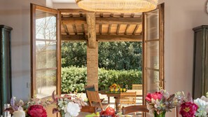 An open wooden structure with a table and chairs, surrounded by greenery and a clear view of trees. - Cosciano 12 Emma Villas (Pomarance)