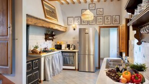 A kitchen with a stainless steel refrigerator, a wooden ceiling, and a tiled backsplash. - Cosciano 12 Emma Villas (Pomarance)