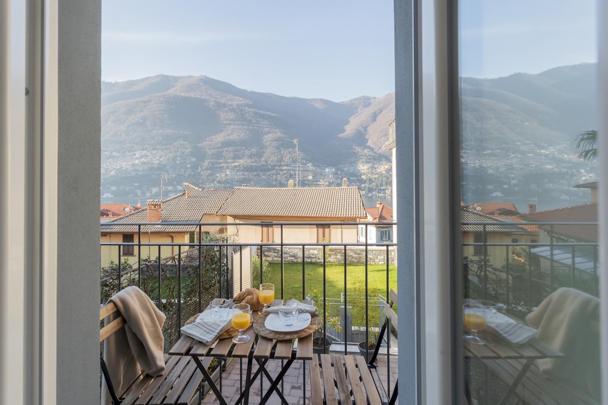 A balcony with a table set for breakfast, overlooking a mountainous landscape.
