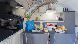 A modern kitchen with a stone arch, a blue bag, and breakfast items on the counter. - Pozzo Vertical Apartment With Garden and Parking (Torno)