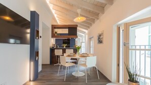 A modern kitchen with white cabinets, a built-in oven, and a dining area with white chairs and a round table. - Muralto s Nest in Como (Como)