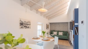 A modern living room with a green sofa, a dining area with a round table, and a kitchen visible in the background. - Muralto s Nest in Como (Como)
