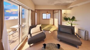 A modern living room with two sofas, a dining table, and a large window offering a city view. - CityLife miyako L'avenir (Miyakojima)