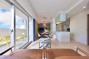 A modern living room with a large window, a dining area, and a kitchen.