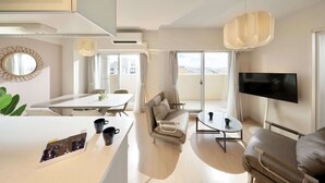 A modern living room with a sofa, a dining table, and a TV. - CityLife miyako L'avenir (Miyakojima)