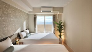 A hotel room with a large bed, a potted plant, and a view of the sea through a sliding door. - CityLife miyako L'avenir (Miyakojima)