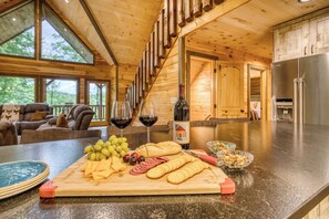 Un intérieur en bois avec un comptoir de cuisine où sont exposés des aliments et des boissons, un coin repas avec un canapé et une vue dégagée grâce à de grandes fenêtres.
