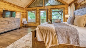 Quarto de cabana de madeira com uma cama, uma televisão, uma cômoda e uma cadeira.