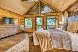 Une chambre dans une cabane en bois, avec un lit, une télévision, une commode et une chaise.