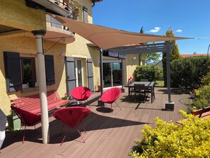 Un patio con sillas rojas, una mesa y una pérgola.