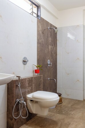 A modern bathroom with a toilet, bidet, and shower. - Hotel Rio Inn (Trimbak)