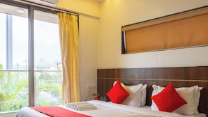 Quarto de hotel com uma cama grande, ventoinha no teto e vista para o verde lá fora.