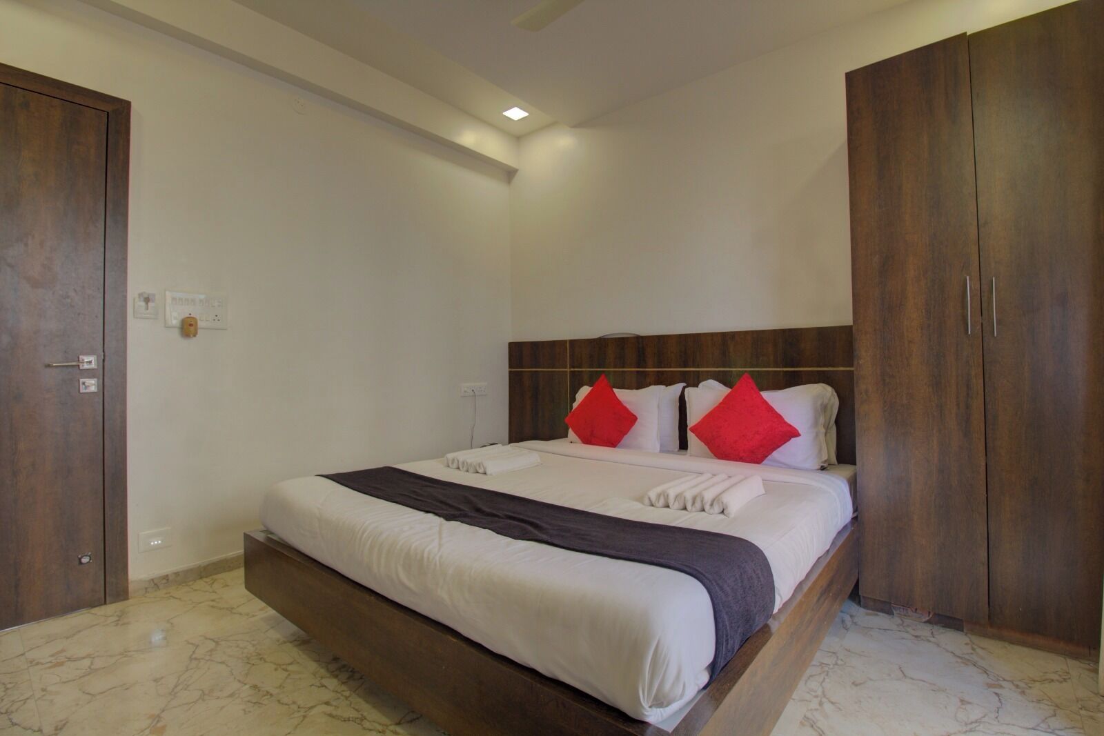 Un dormitorio con cama, armario de madera y suelo de mármol.