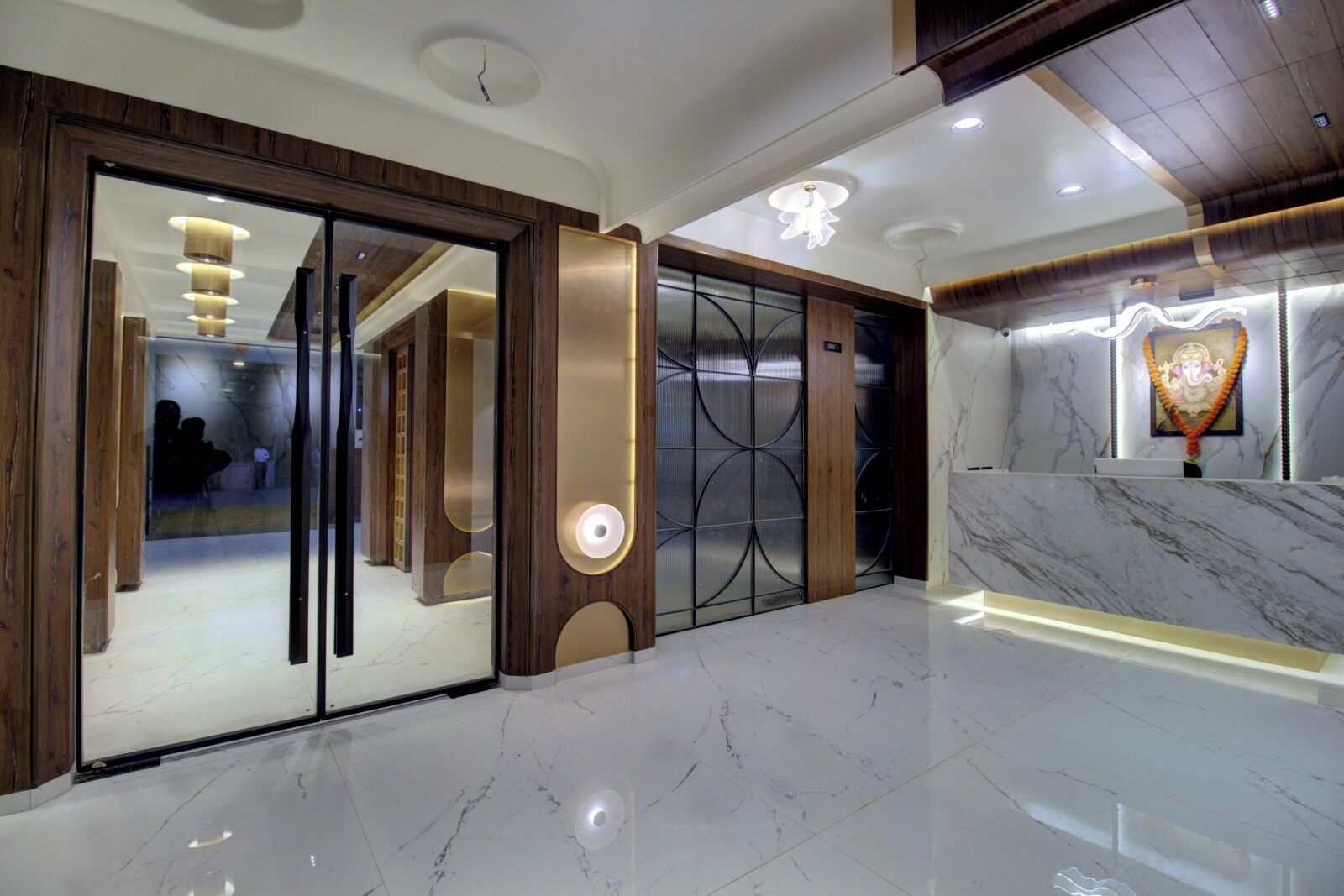 A modern hotel lobby with a marble floor, wooden accents, and a reception area with a heart-shaped light fixture.