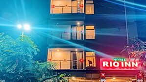Um edifício de vários andares com uma placa grande exibindo 'HOTEL RIO INN'.