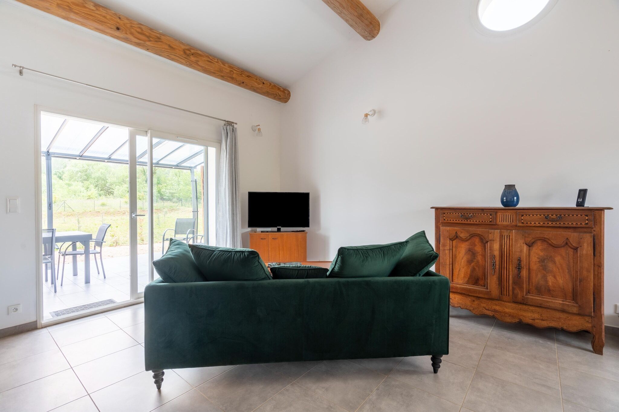 Uma sala de estar com um sofá verde, um armário de madeira e uma televisão de tela plana.
