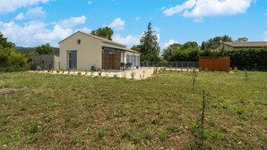 Ein modernes Haus mit einer großen Garage, einer überdachten Terrasse und einem eingezäunten Garten.