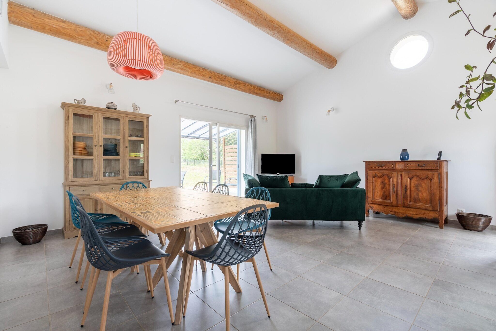 Una habitación amplia con una mesa de comedor de madera, sillas, un sofá verde y un mueble de madera.