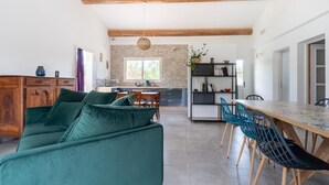 Eine moderne Küche mit Essbereich, ausgestattet mit einem grünen Sofa, einem Holzesstisch und blauen Stühlen.