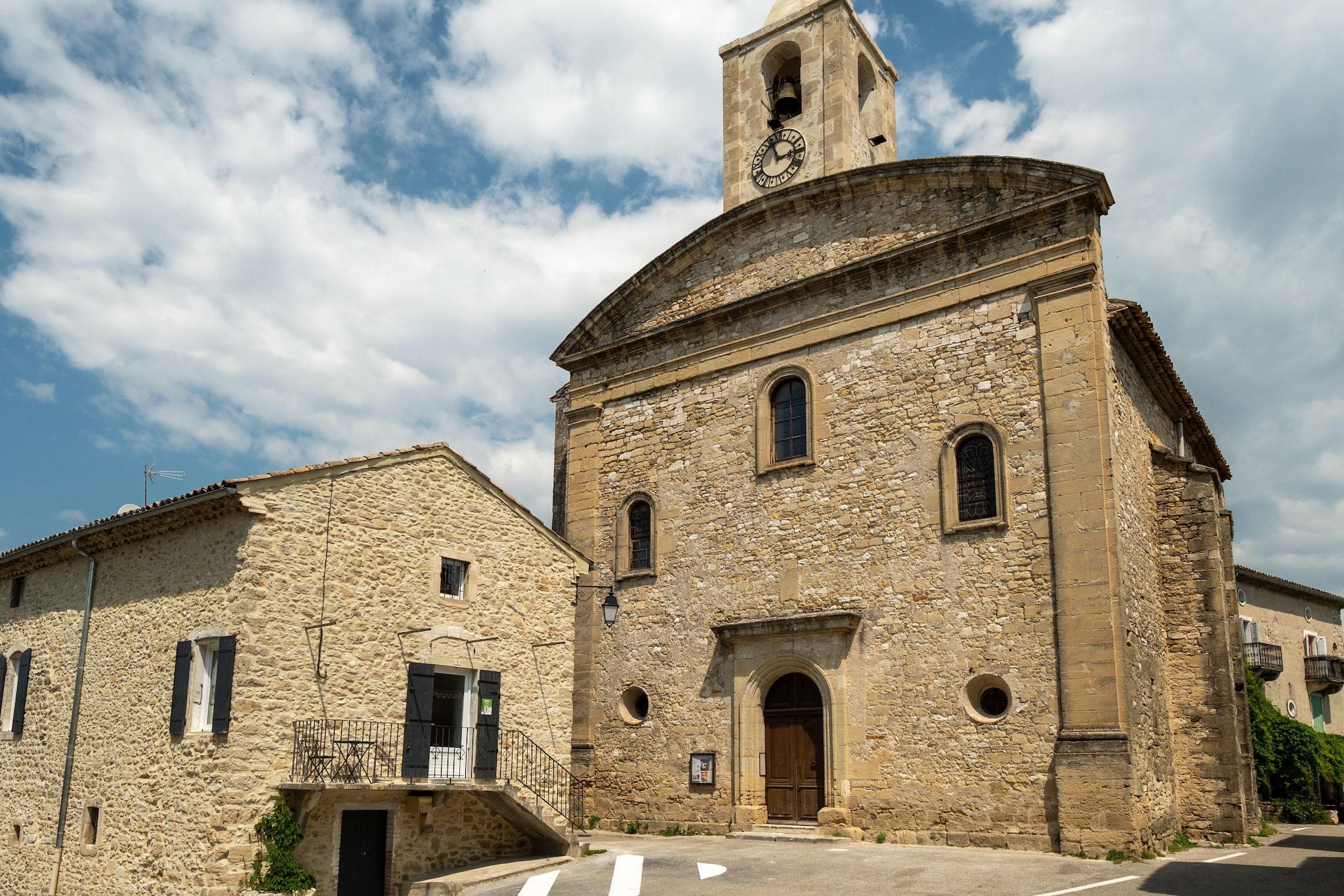 A stone building with a bell tower, arched windows, and a door.