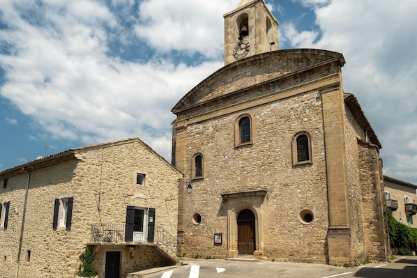 A stone building with a bell tower, arched windows, and a door.