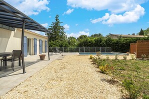 A covered outdoor area with a pool, seating, and a building with blue doors.