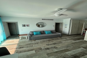 A living room with a grey sofa, a ceiling fan, and a patterned floor.