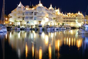Eine Marina mit Yachten und ein großes, markantes Hotel mit zahlreichen Balkonen und einer spiegelnden Wasseroberfläche.